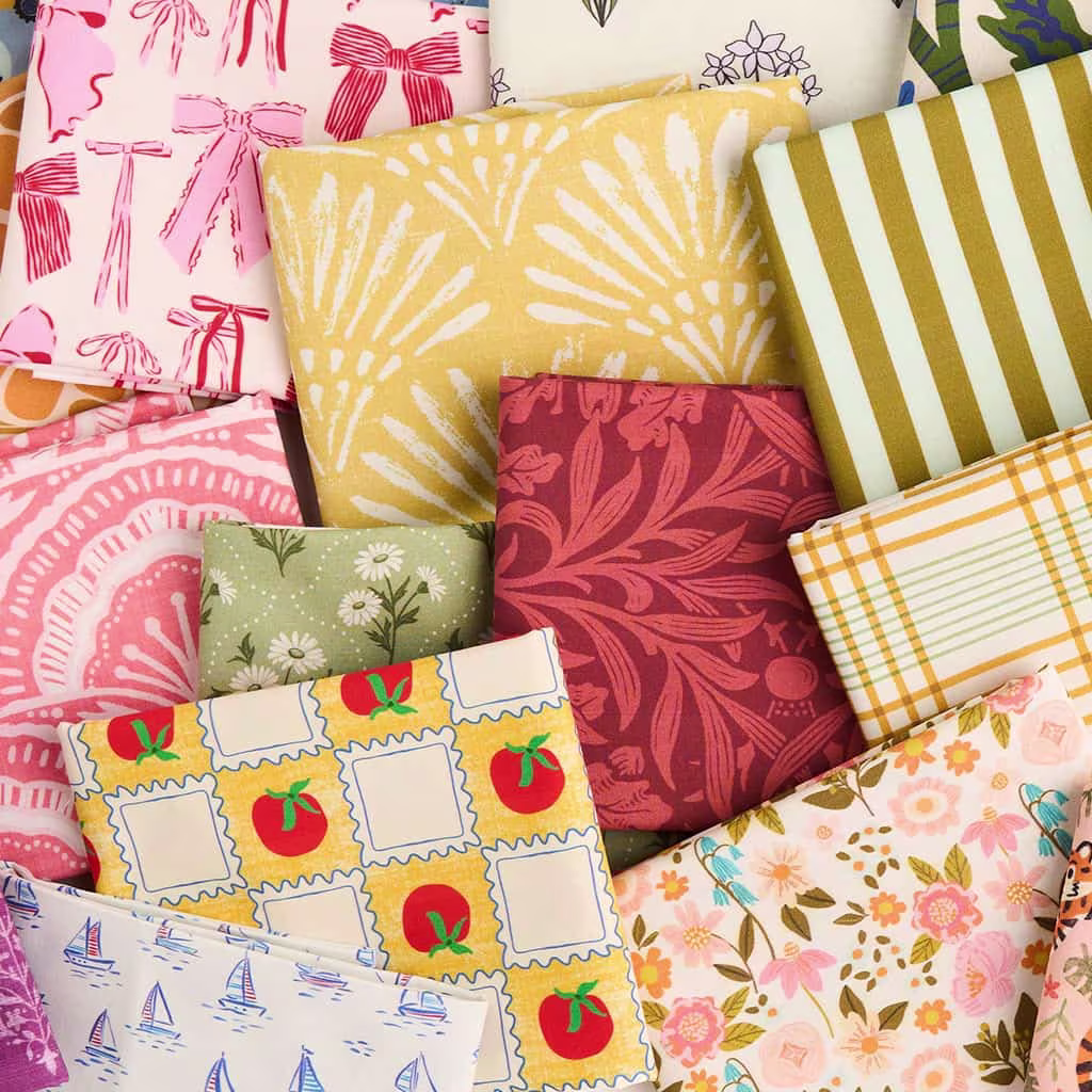 Folded fabrics in assorted colorful patterns arranged in a flat lay