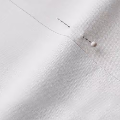 A close-up photo of white fabric with a pin running through it