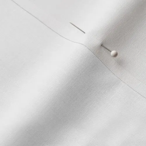 A close-up photo of white fabric with a pin running through it