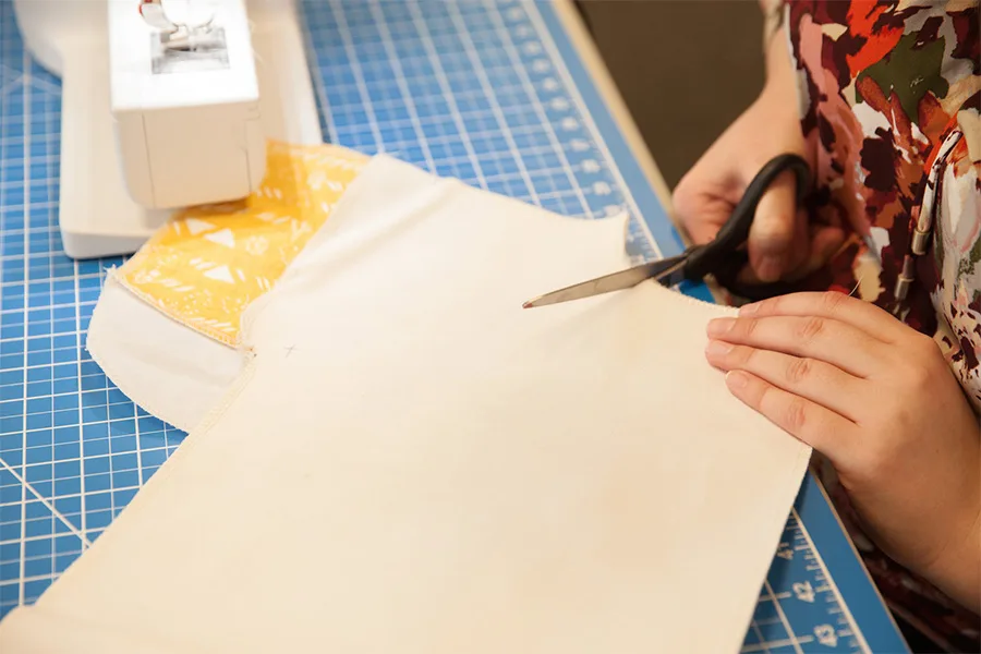 MaryAshlyn cutting along the curve of her denim pieces that are making the front pocket.