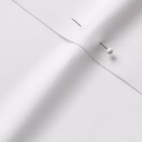 A close-up photo of white fabric with a pin running through it