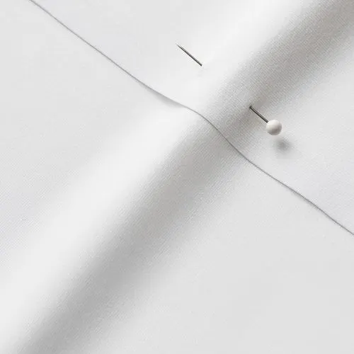 A close-up photo of white fabric with a pin running through it