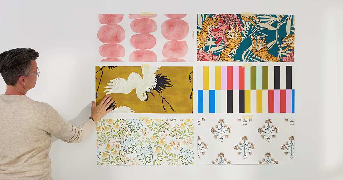 Person assessing 6 wallpaper samples on a wall.