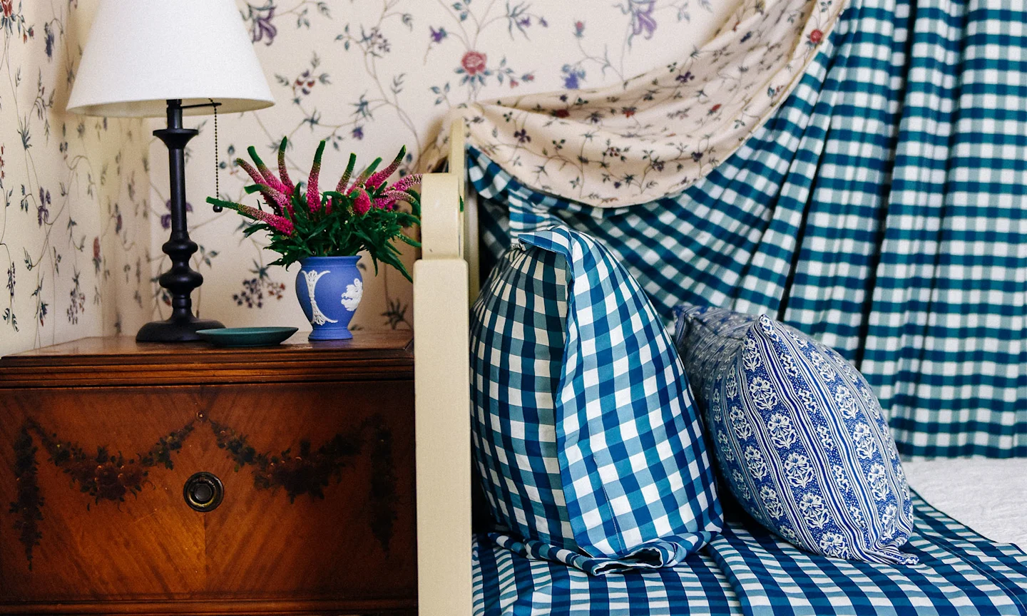 Bedroom with blue gingham bedding and a matching canopy curtain.