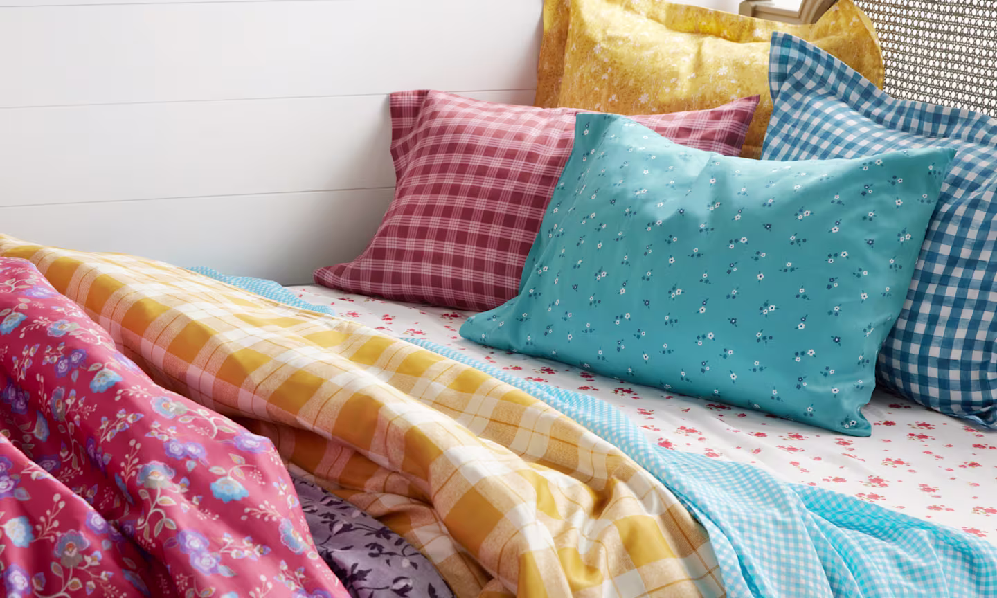 Bed layered with sheets, pillows, and duvet covers in an assortment of french country designs.