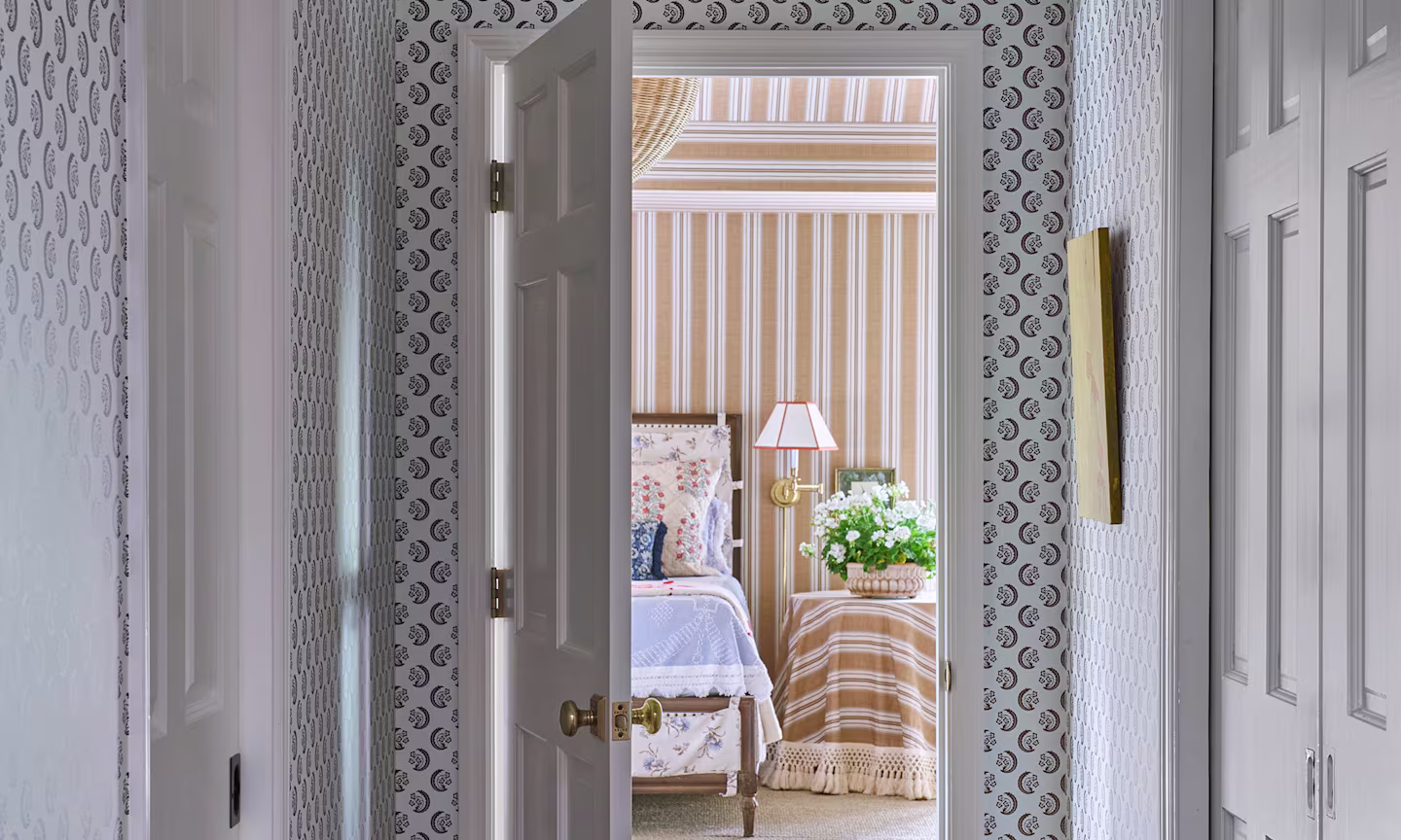 Hallway with wallpaper in Saz Crescent design and a bedroom with a tan stripe wallpaper.