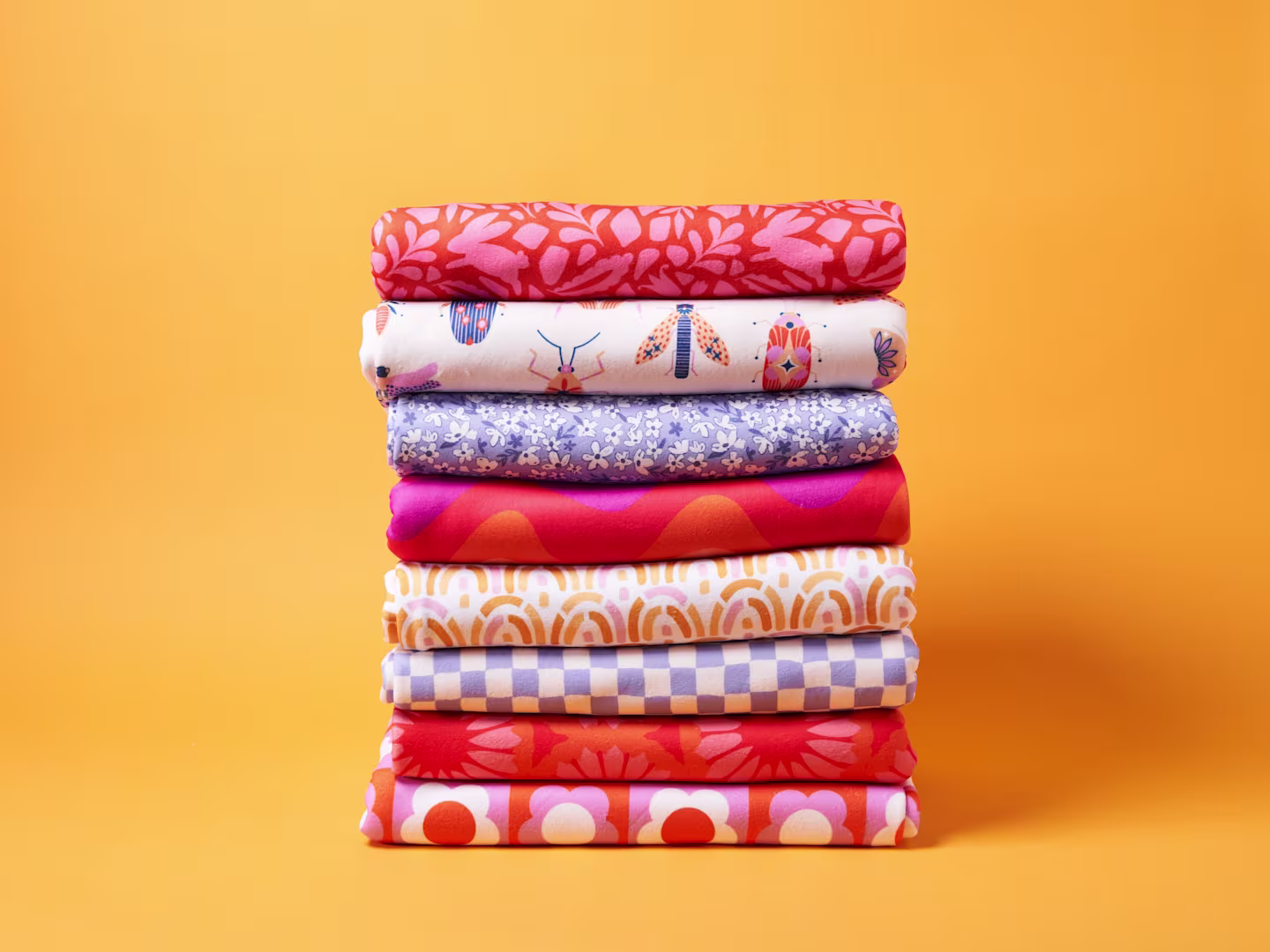 A stack of Polartec Fleece in bright and punchy colors