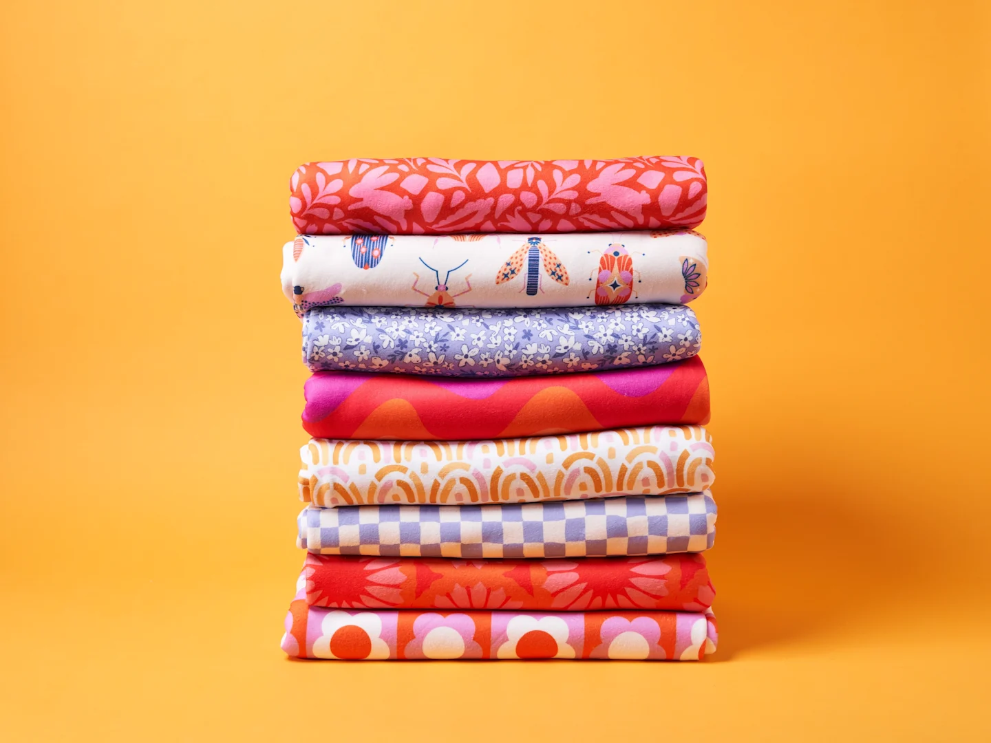 A stack of Polartec Fleece in bright and punchy colors