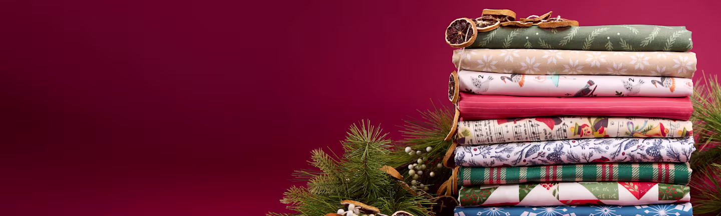 Stack of Christmas print fabrics on red background