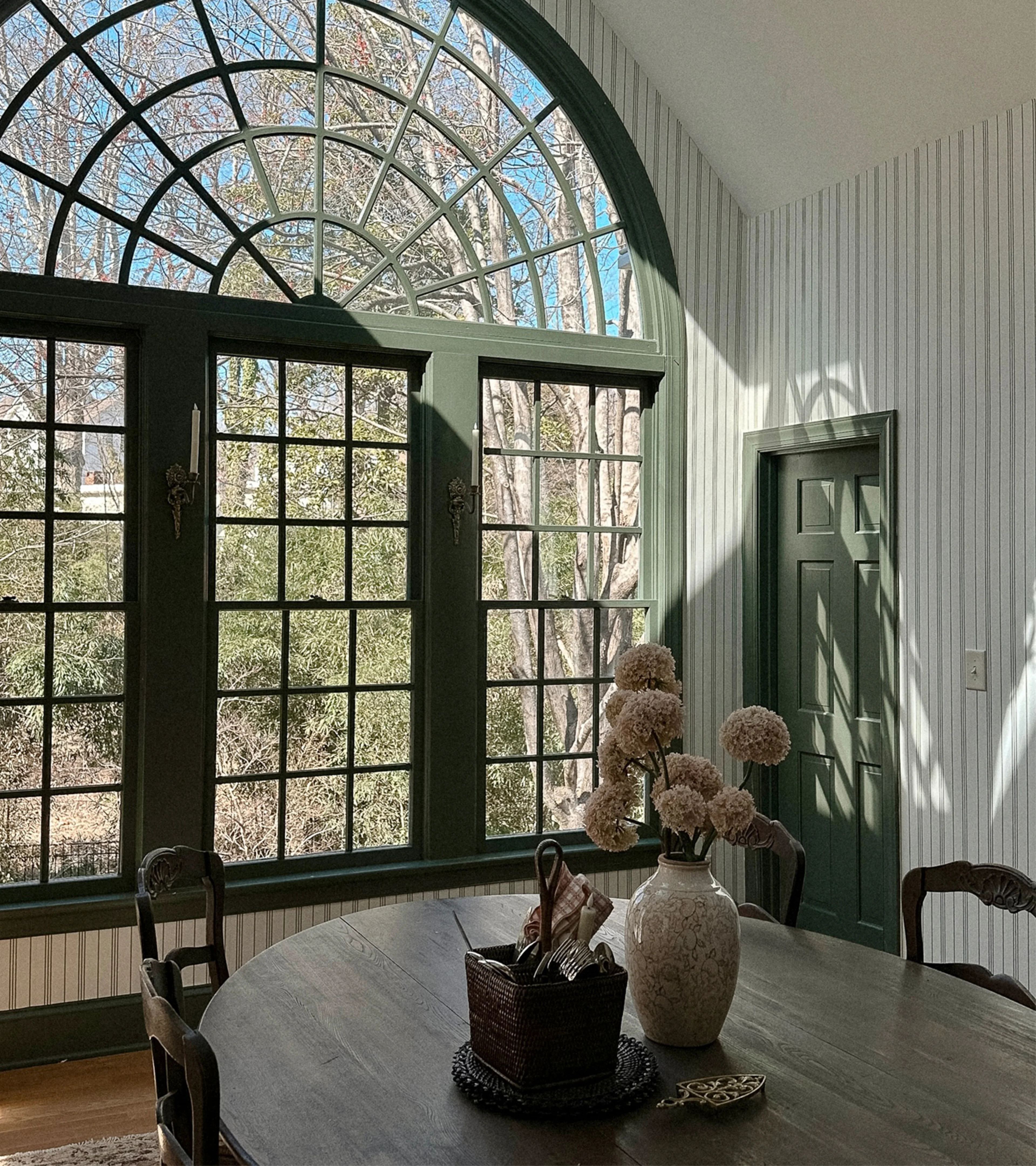 Dining area with striped wallpaper and large windows.