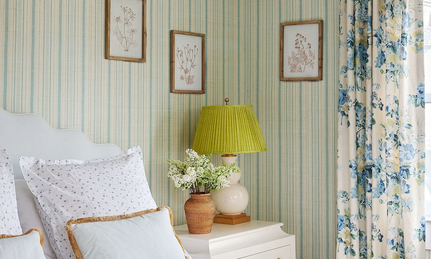 Bedroom with striped wallpaper and floral curtains.