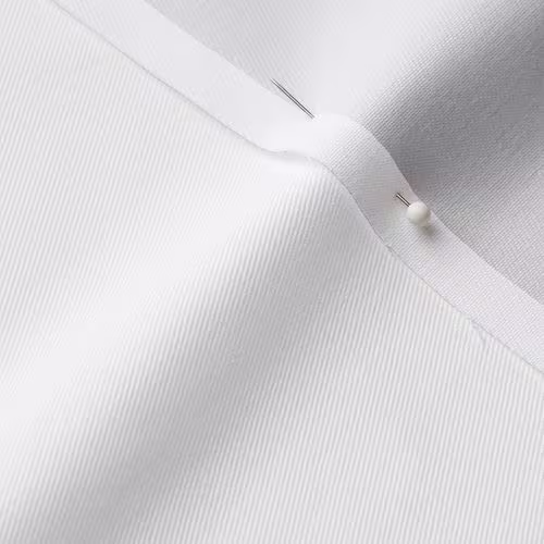 A close-up photo of white fabric with a pin running through it