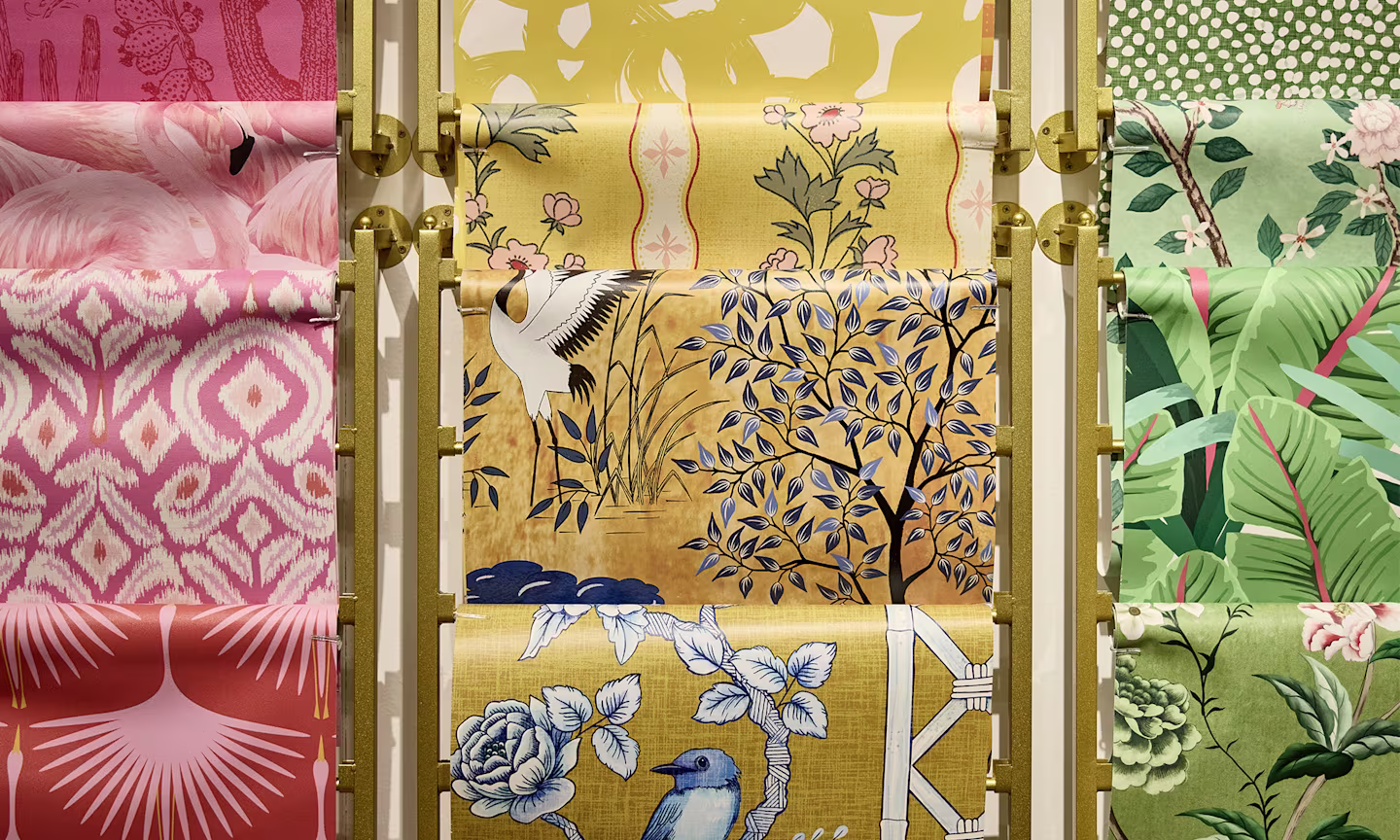 Pink, yellow and green rolls of Spoonflower wallpaper with unique patterns.