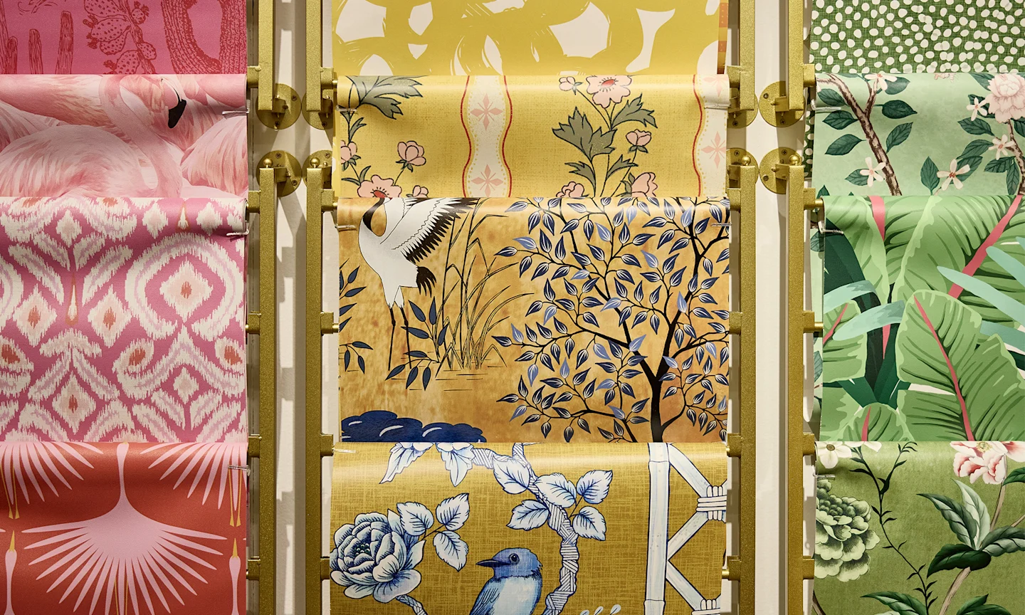 Pink, yellow and green rolls of Spoonflower wallpaper with unique patterns.