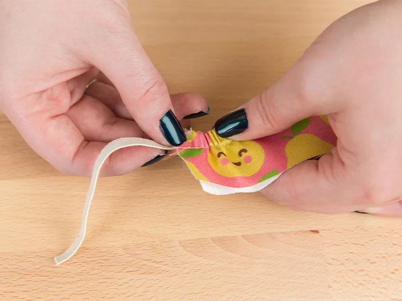 A women is threading the elastic through the casing with her hands,
