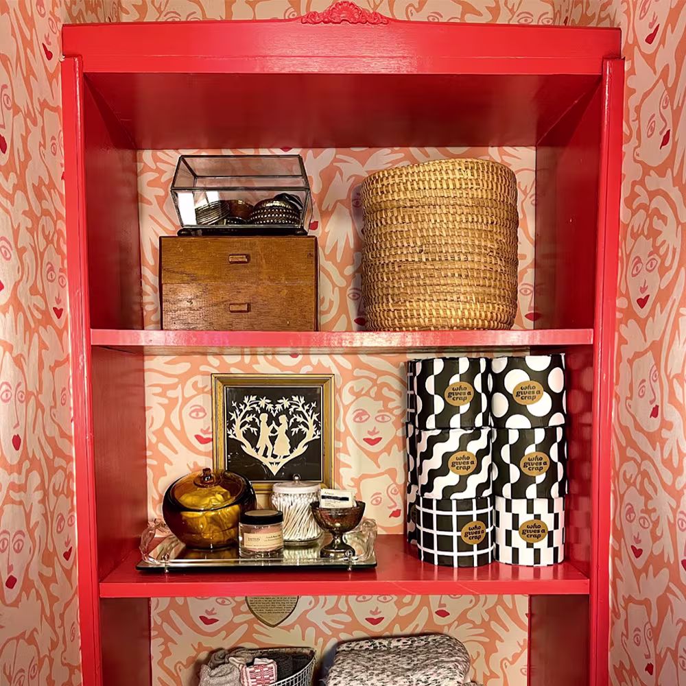 Peach face wallpaper behind a red shelf.