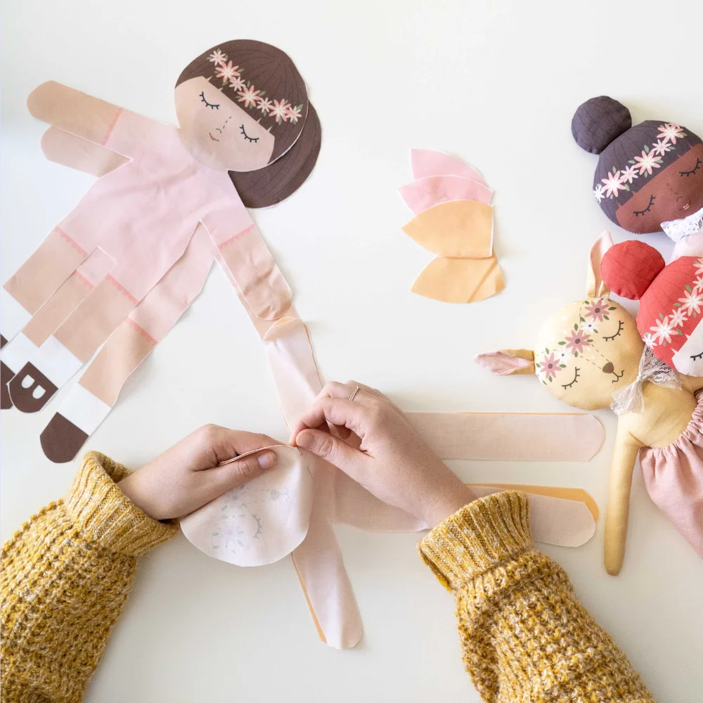 little kids hands working on a cut and sew doll.