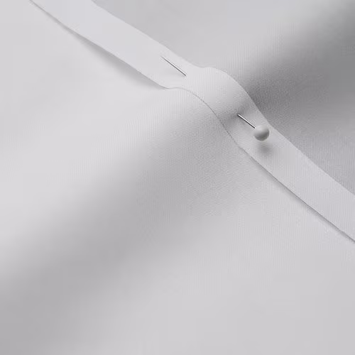 A close-up photo of white fabric with a pin running through it
