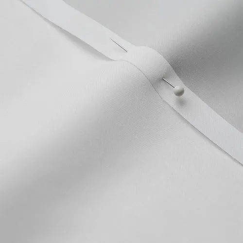 A close-up photo of white fabric with a pin running through it
