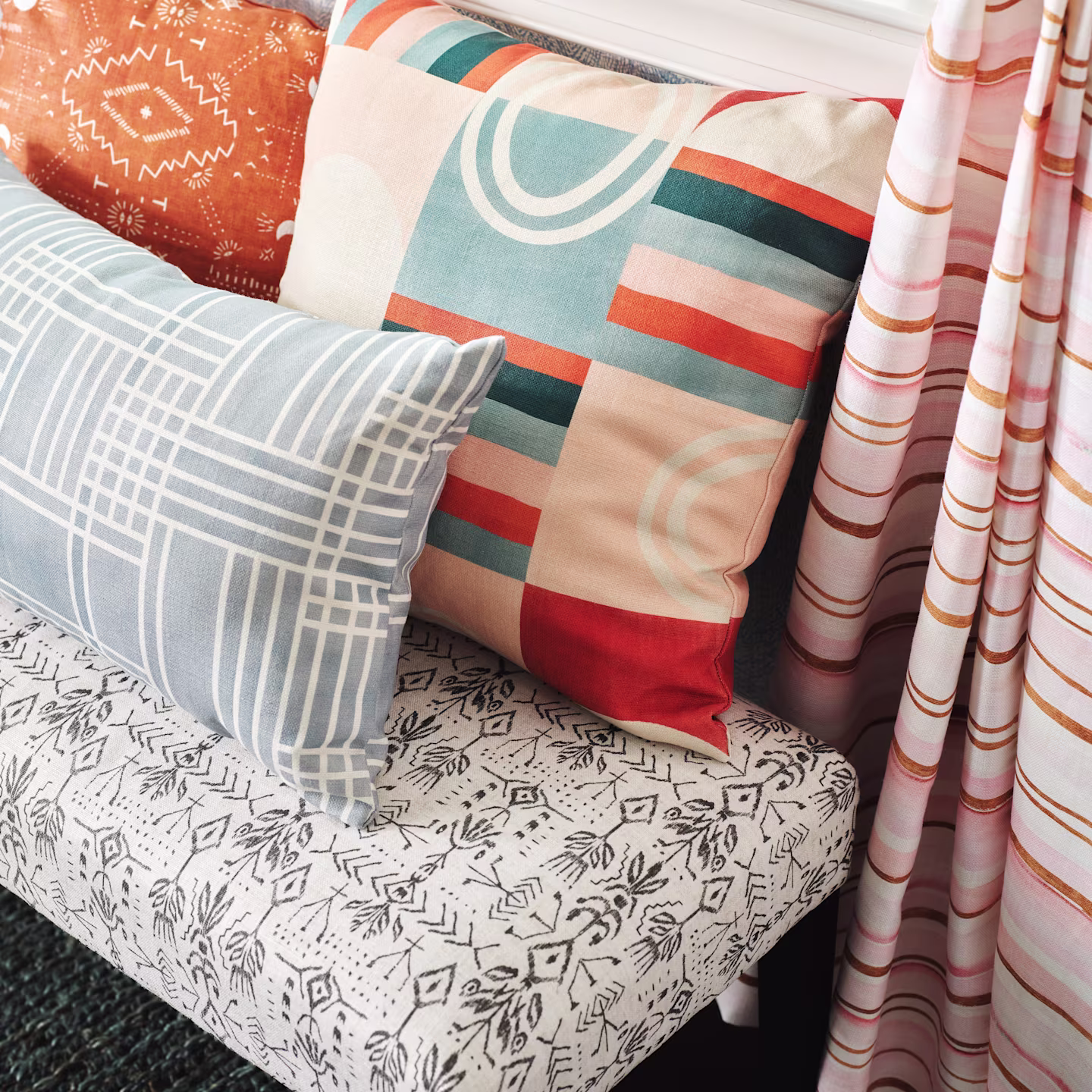 Upholstered bench with throw pillows and curtain