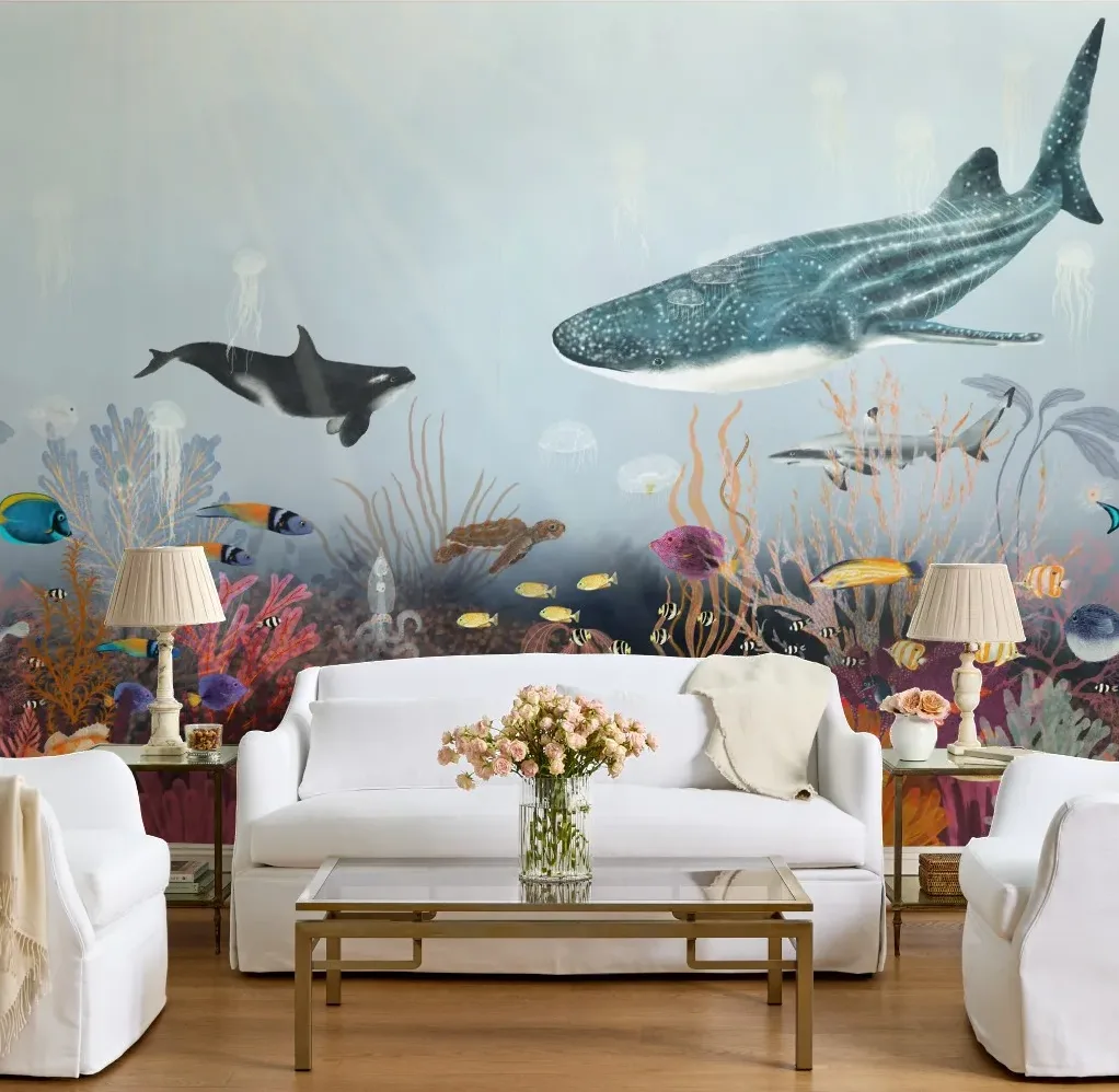 Living room featuring an underwater ocean mural with a whale shark, orca, colorful coral reef, tropical fish, and sea life spanning the wall behind a white sofa.
