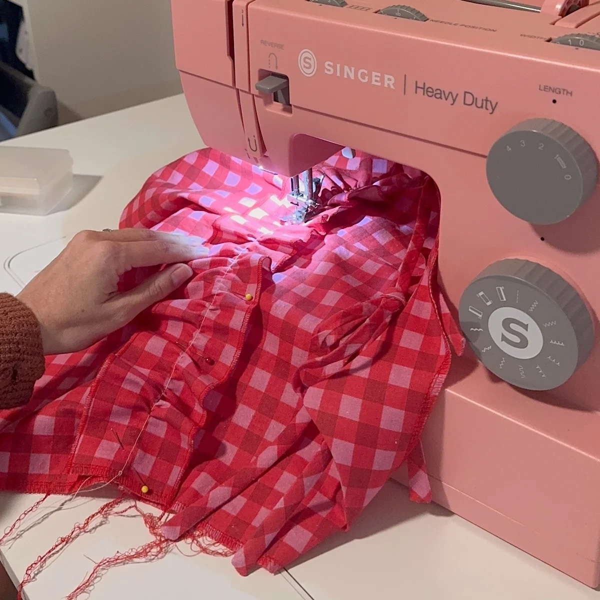 a pink and white dress being sewing on a pink sewing machine.