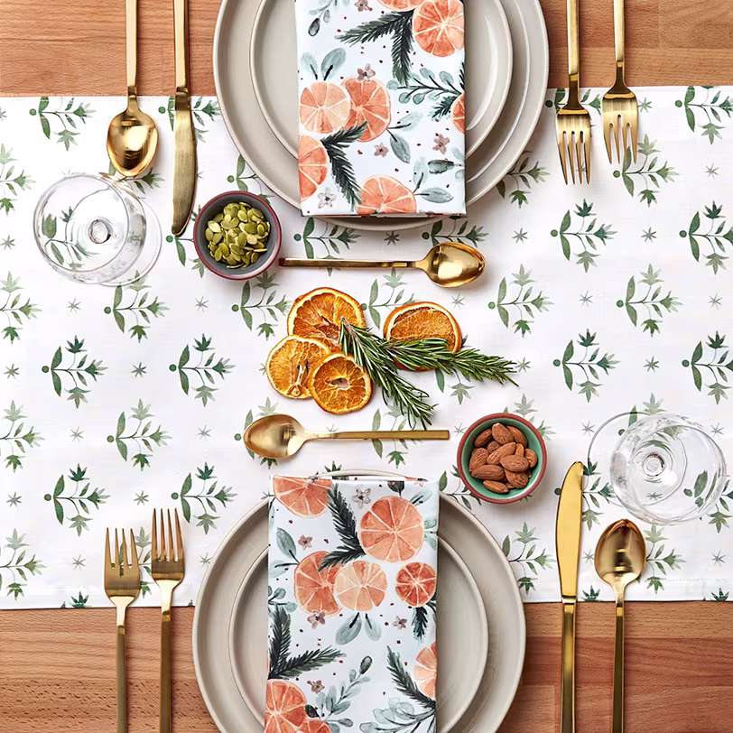 Table set with festive oranges and greenery runner and napkins.