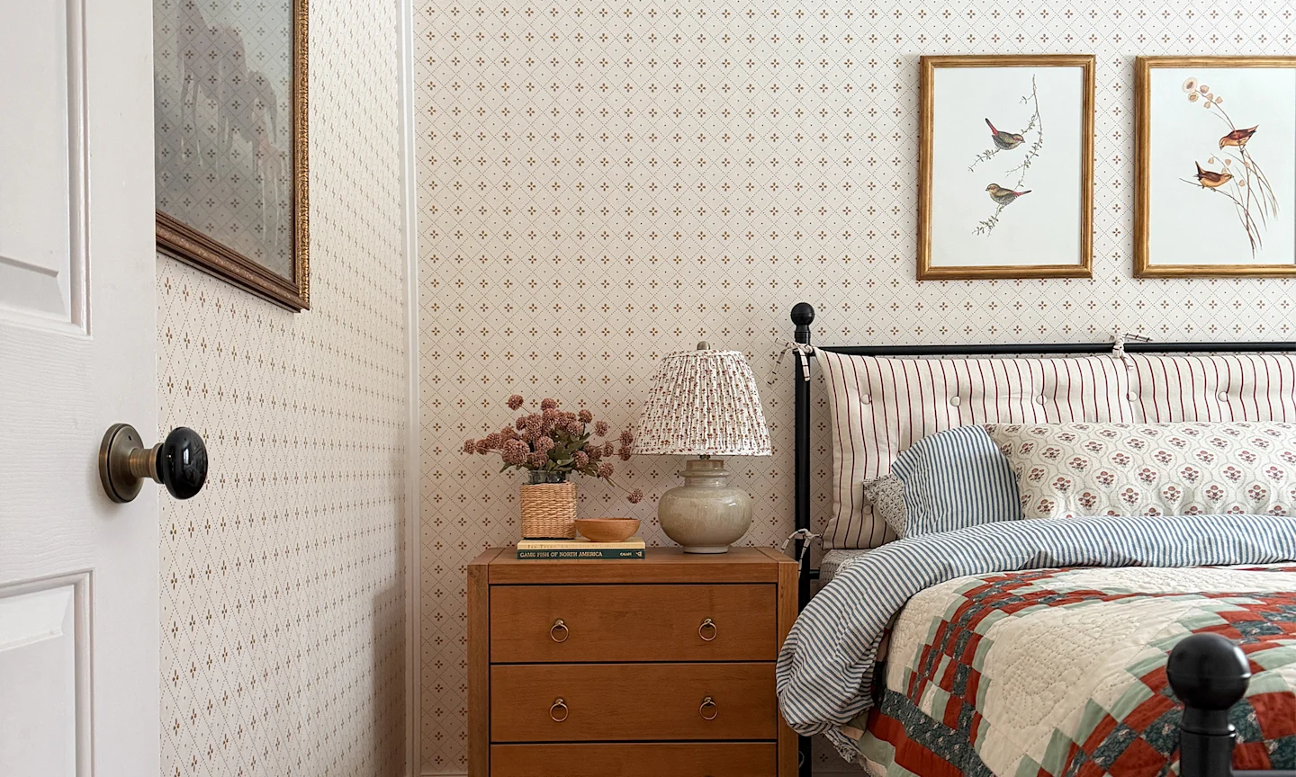 Cabin bedroom with neutral wallpaper and coordinating bedding.