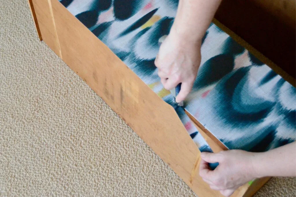 Barb cutting the excess wallpaper from a dresser drawer using a craft knife.