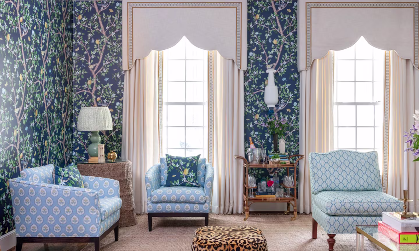 A formal living room with leopard stools and navy blue floral wallpaper.
