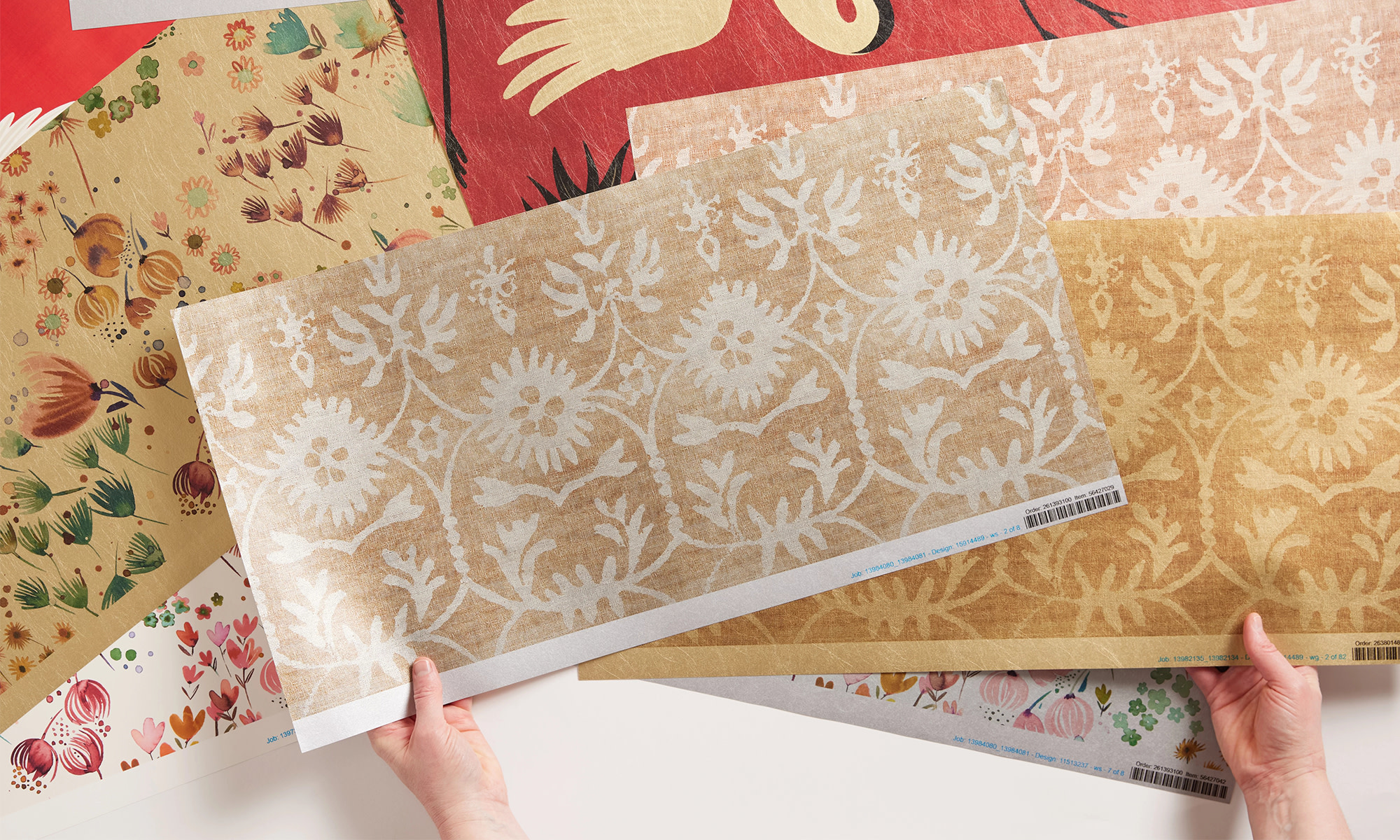 Hands holding metallic wallpaper swatches.