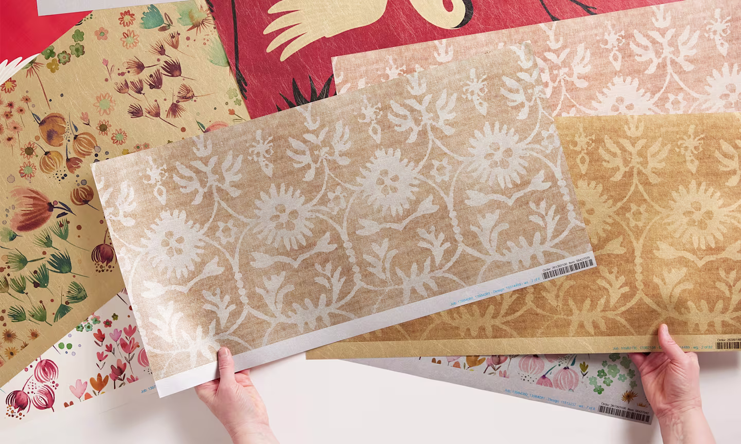 Hands holding metallic wallpaper swatches.