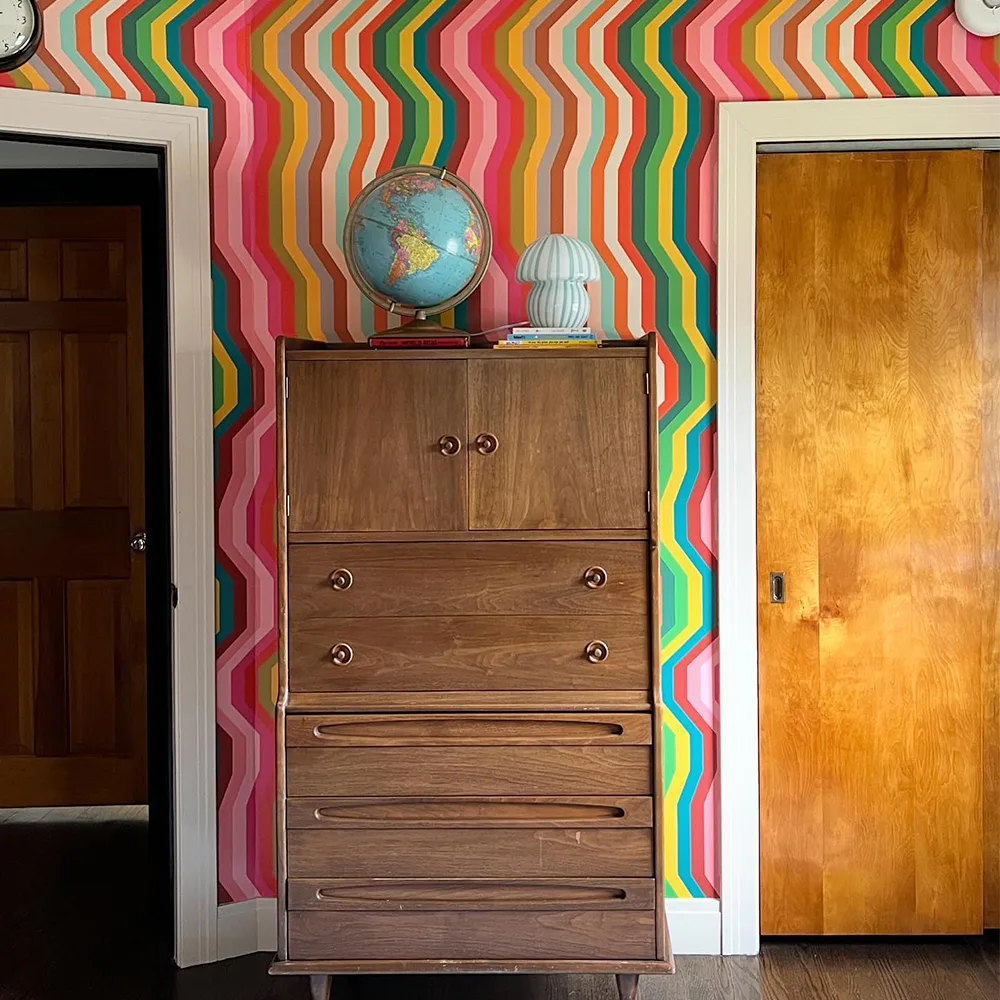 Wavy stripe wallpaper behind a dresser.