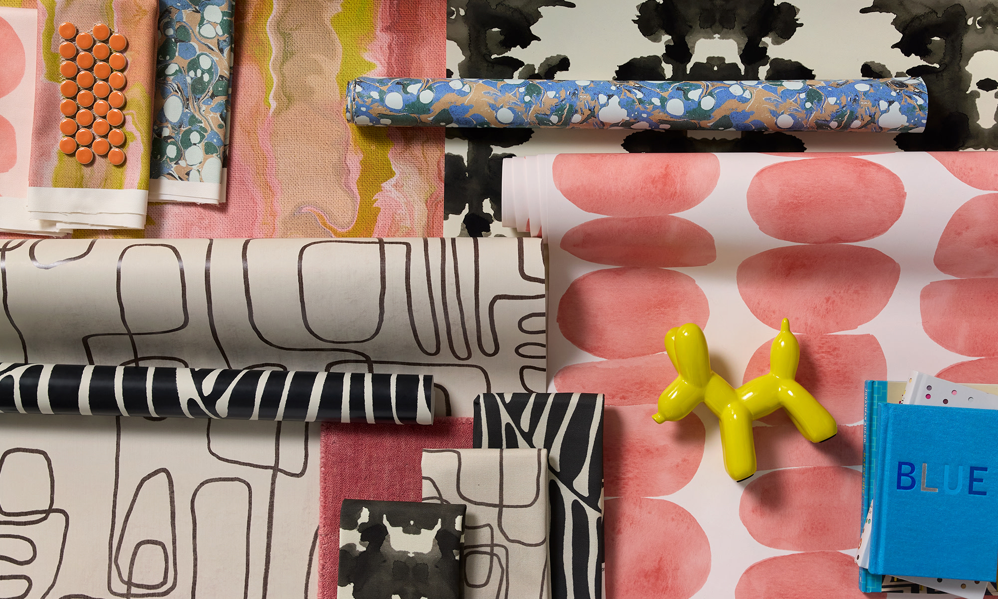 Modern style wallpaper rolls and fabric swatches.