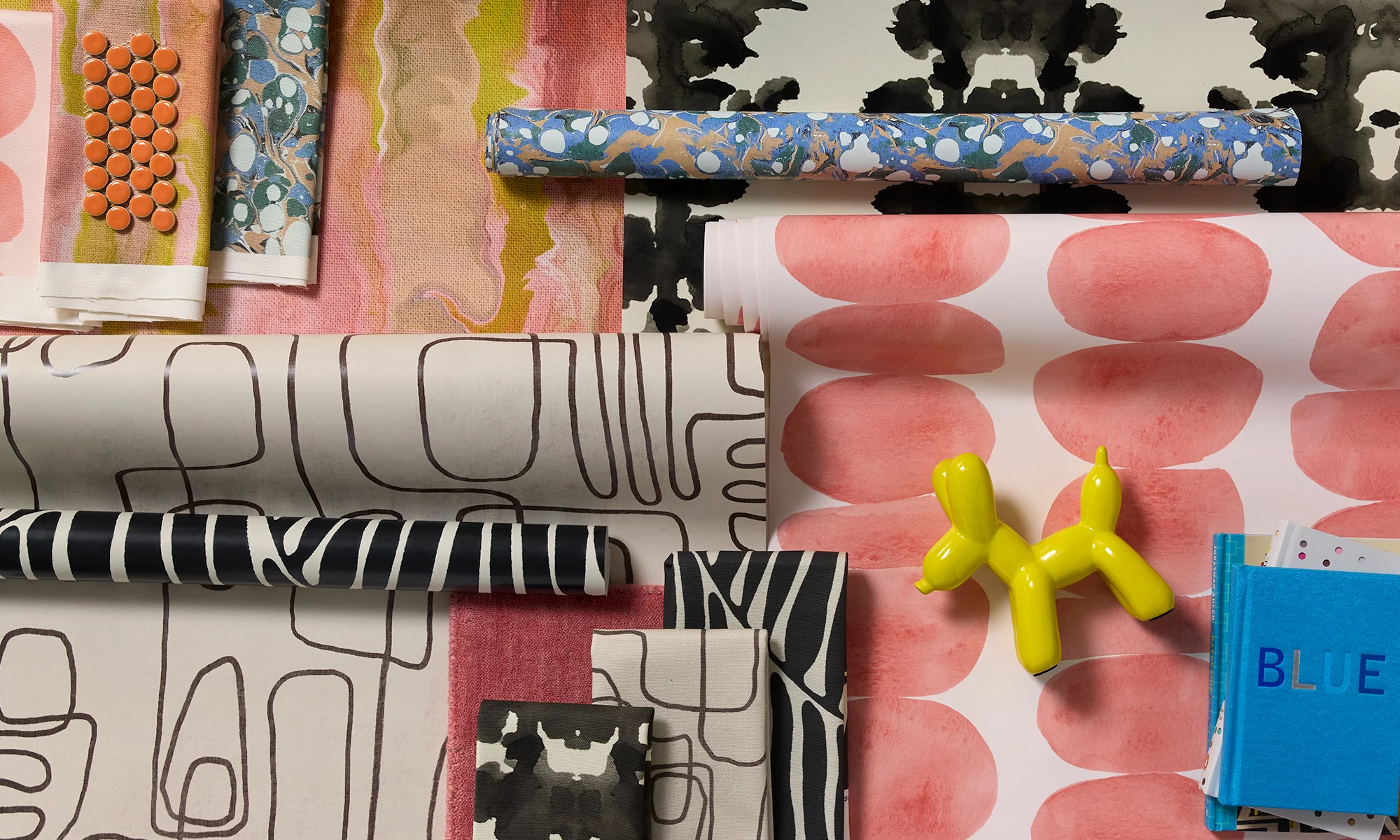 Modern style wallpaper rolls and fabric swatches.