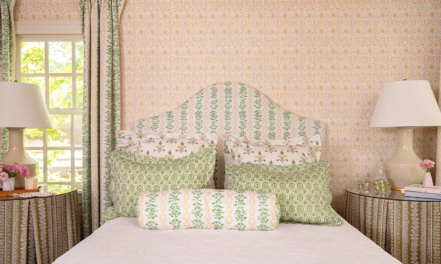 Bedroom with yellow floral wallpaper and floral bedding.