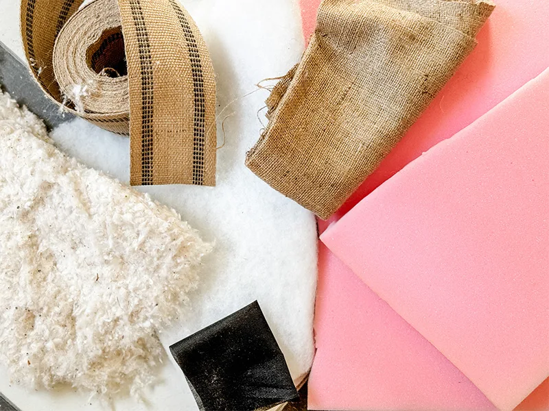 Cotton, jute webbing, burlap, medium density foam lay gathered on a surface.