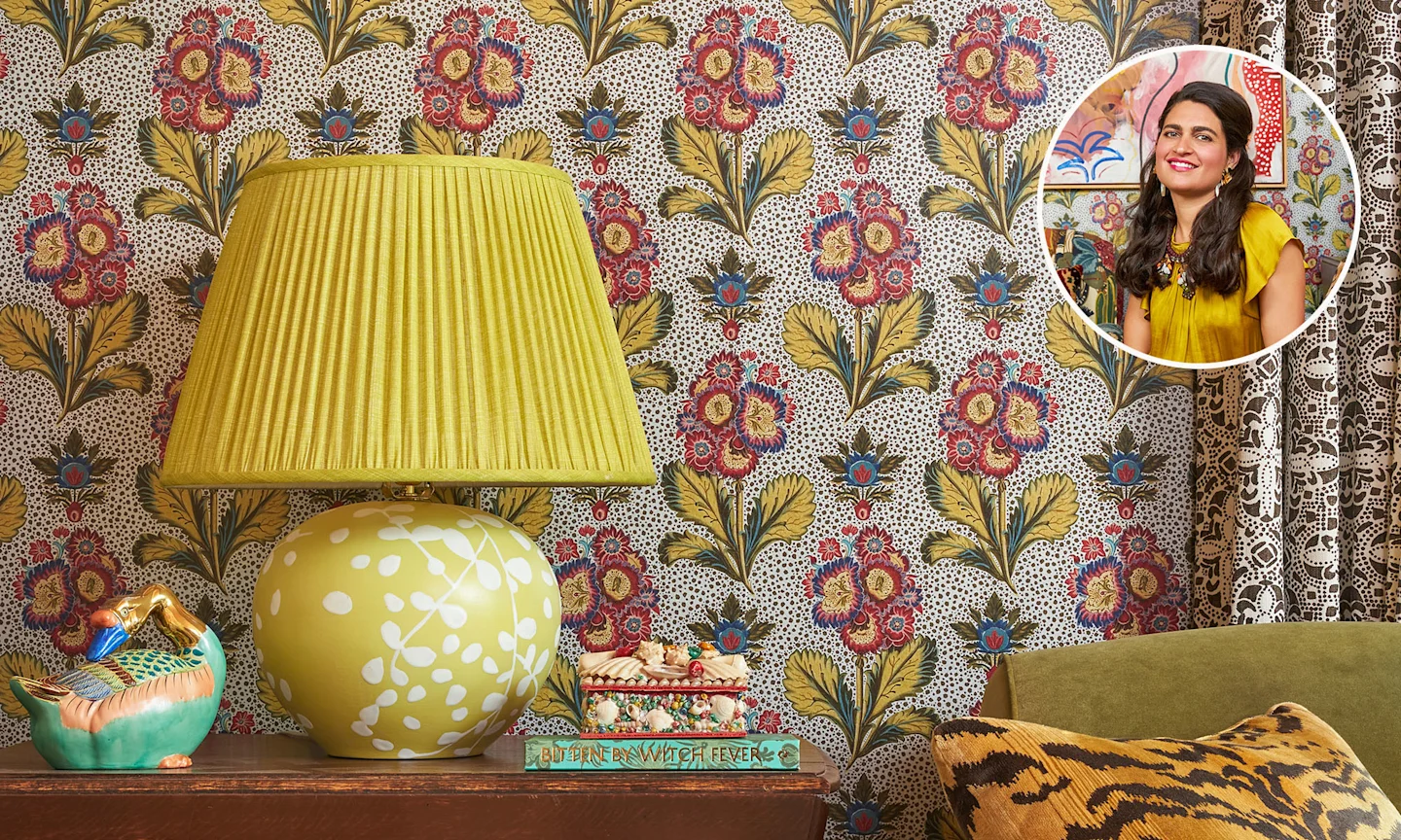 Floral silver wallpaper, with a side table, green couch, pillow, and a yellow lamp.
