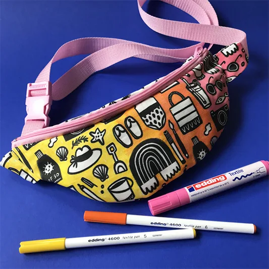 Fanny pack and fabric markers on blue background