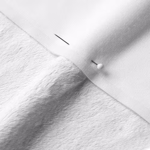 A close-up photo of white fabric with a pin running through it