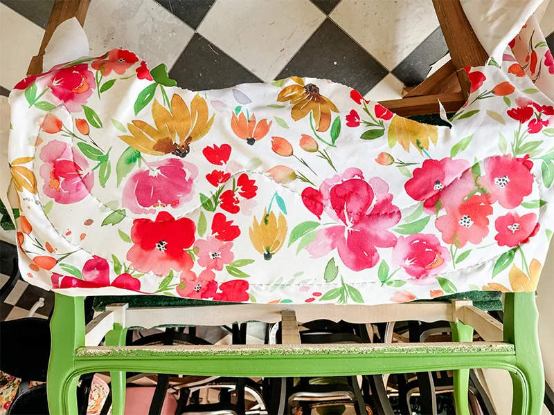 Floral fabric is stapled to the back of her settee top.
