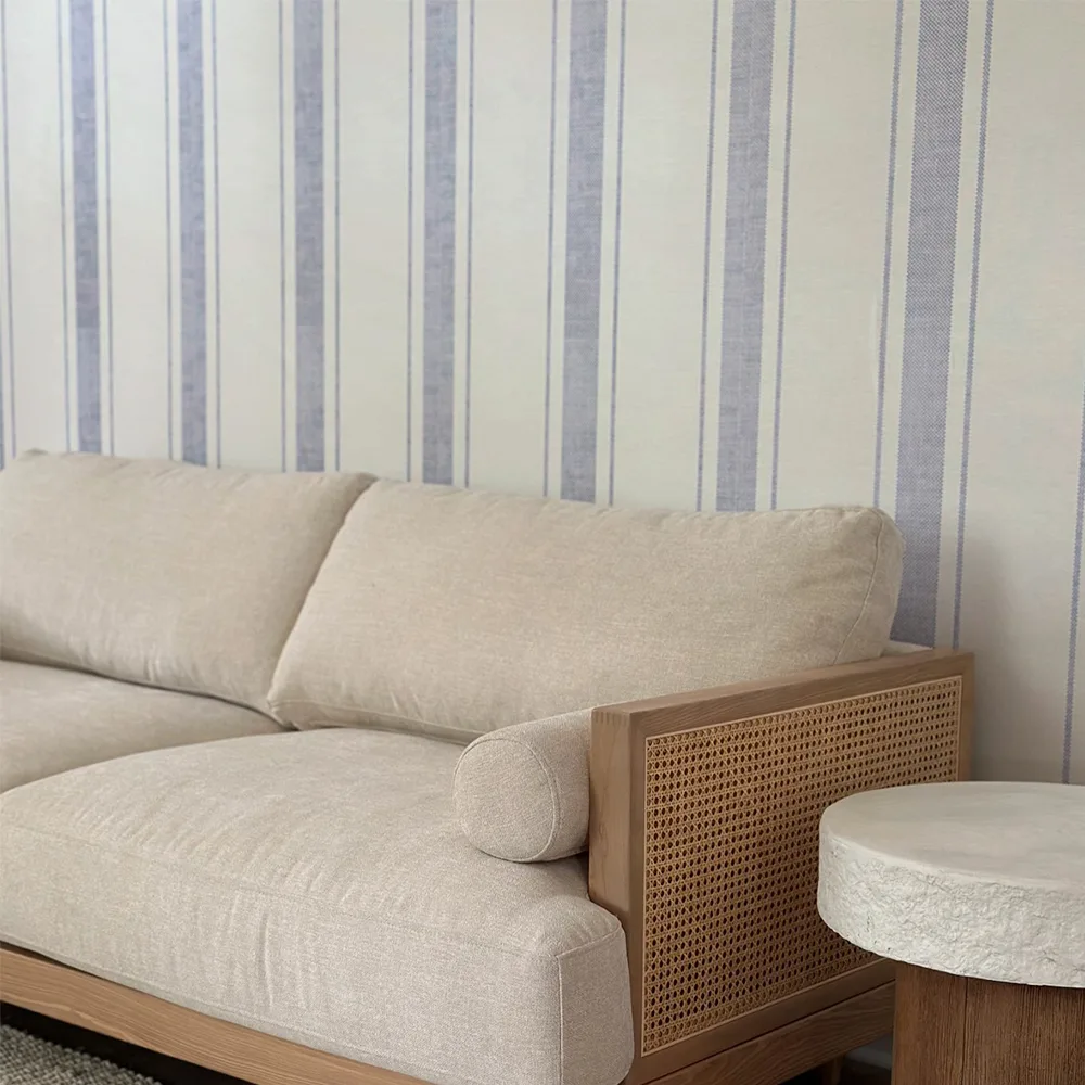 Blue striped coastal wallpaper behind a couch.