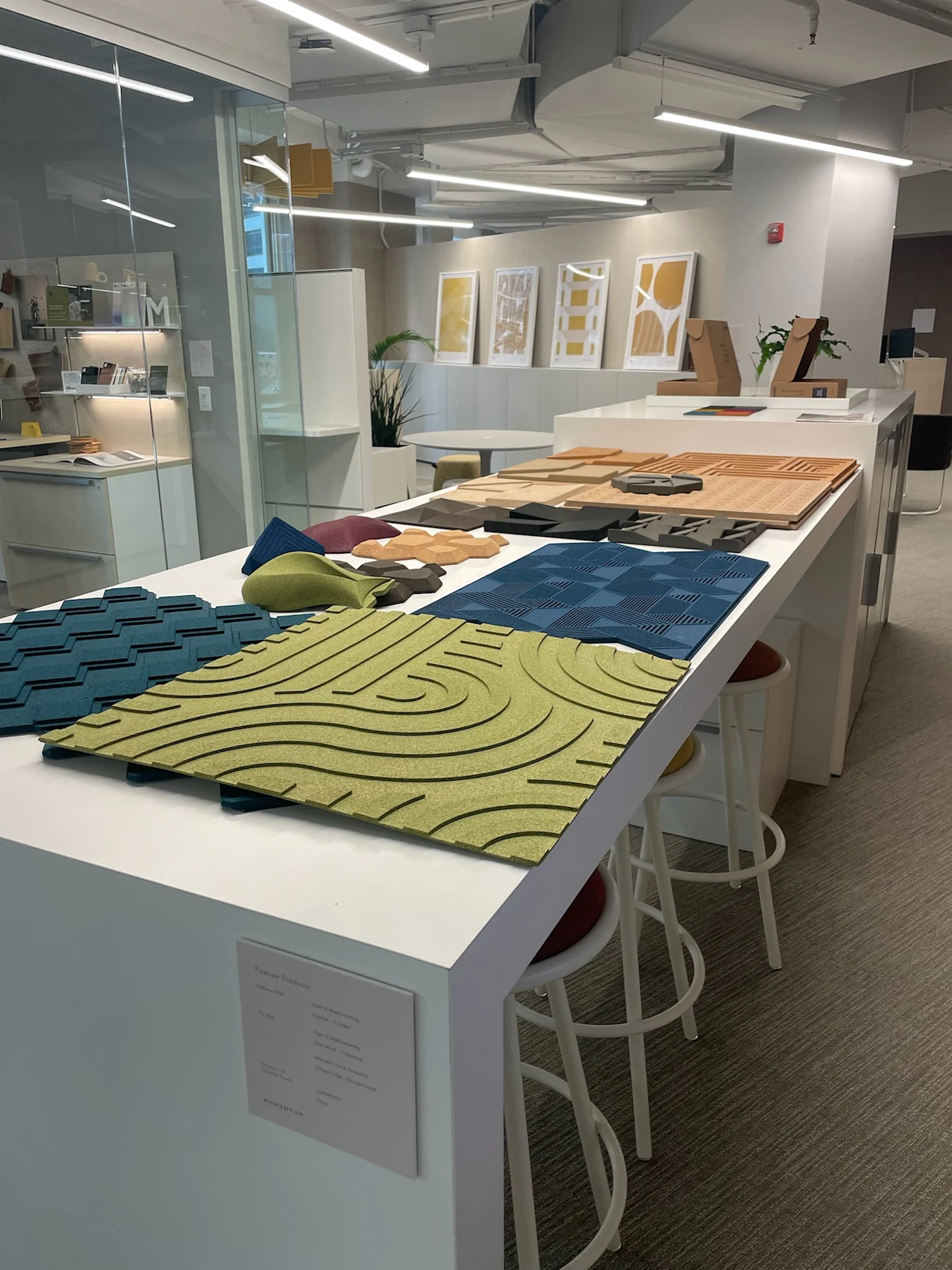 Textured acoustic wall panels and geometric material samples displayed on a worktable in a modern design showroom