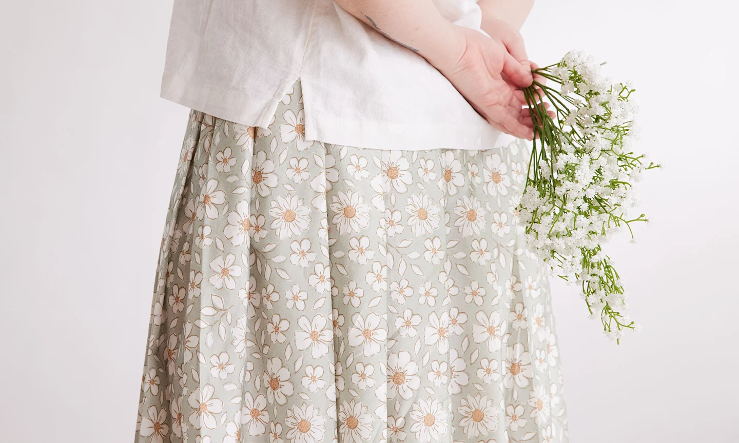 A person wearing a skirt made with a sage green and cream floral design