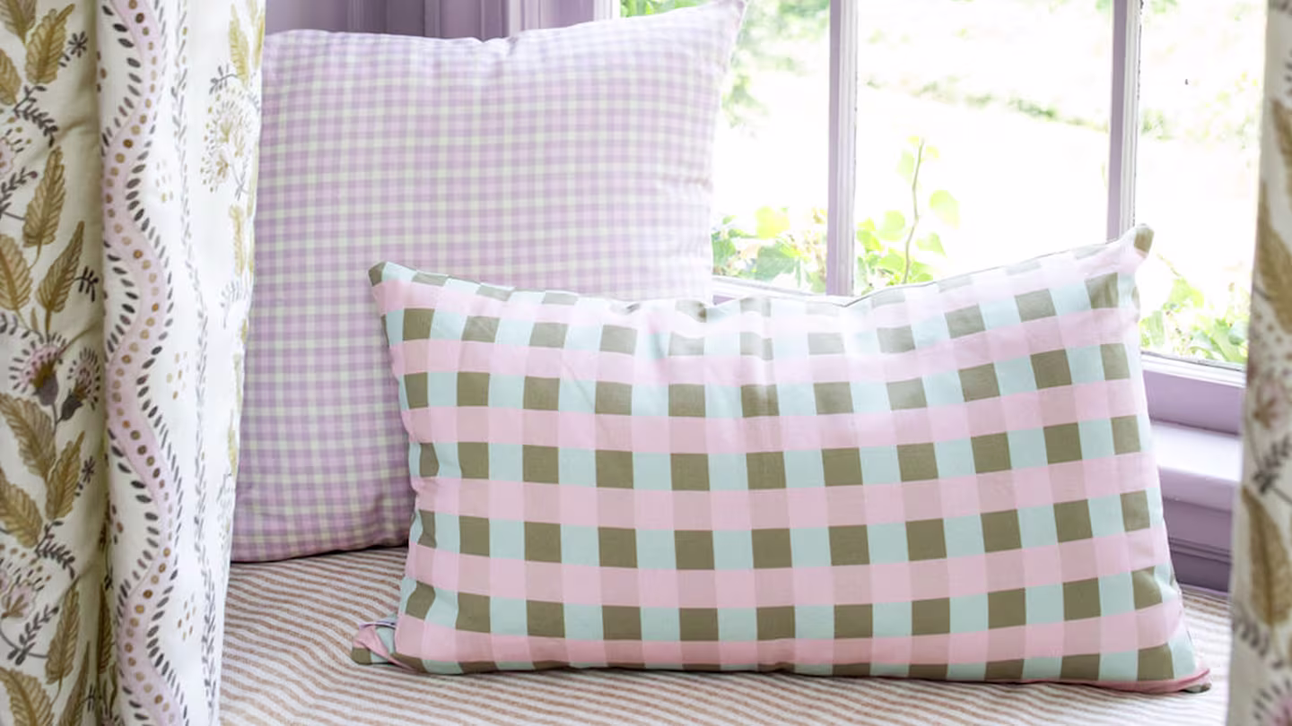 Plaid pink window seating with long rectangular pillow.