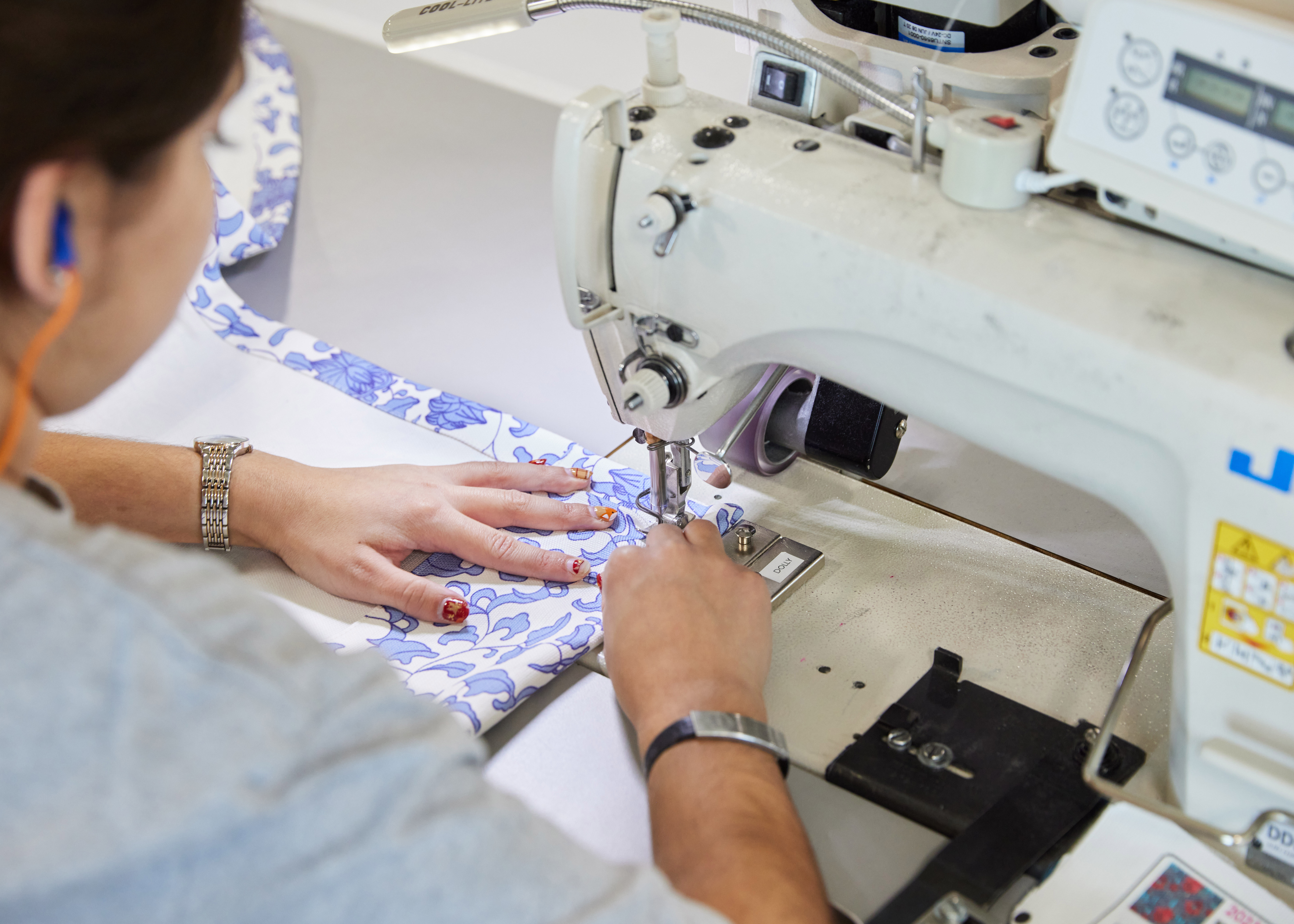over the shoulder view of seamstress sewing fabric on sewing machine