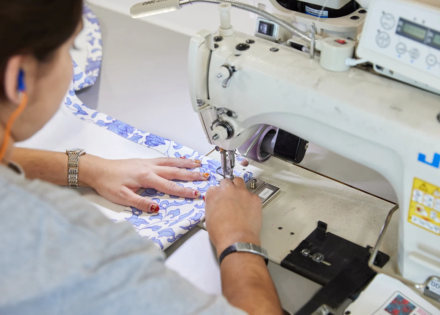 over the shoulder view of seamstress sewing fabric on sewing machine