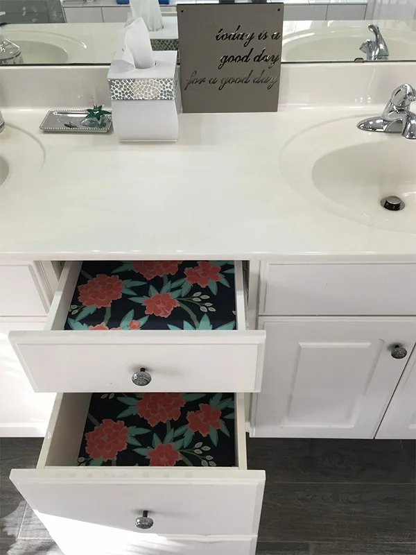 Two open drawers lined with wallpaper are in a bathroom .