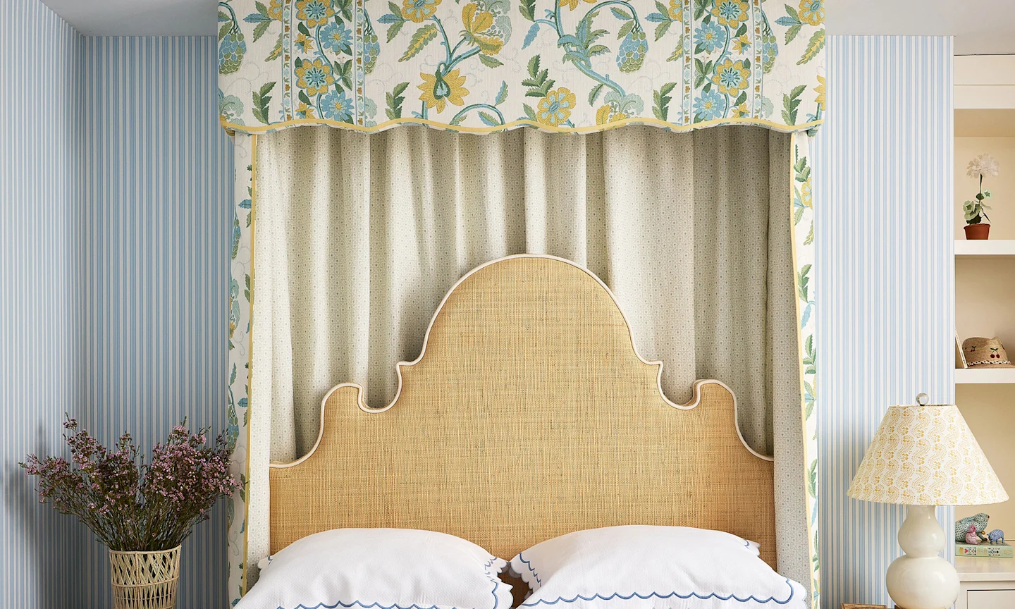 Bedroom with blue striped wallpaper and a bed with a cornice headboard.