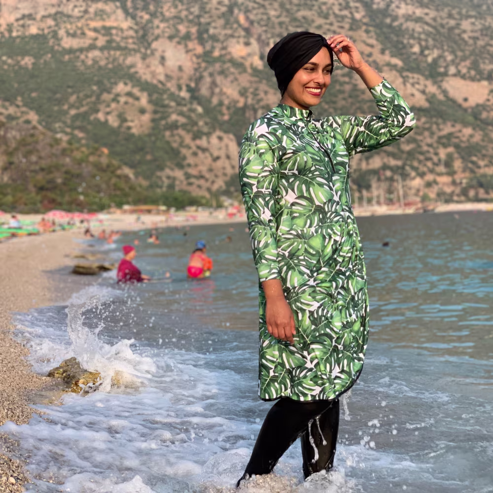 Woman wearing modest swimsuit in monstera print sport lycra